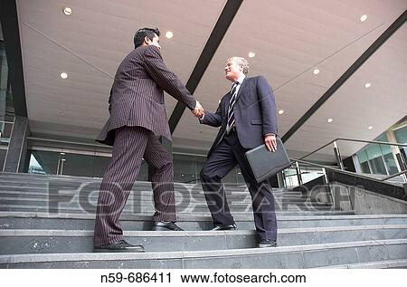 Businessmen shake hands outside an office View Large Photo Image Stock Image - Businessmen shake hands outside an office. Fotosearch