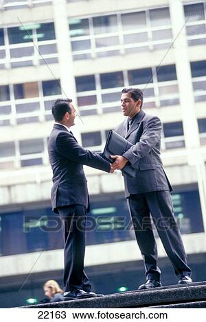 Businessmen shaking hands in the street View Large Photo Image Stock Image - Businessmen shaking hands in the street. Fotosearch