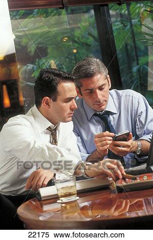 Businessmen working in a hotel lobby using electronic organizer View Large Photo Image Stock Photography - Businessmen working in a hotel lobby using electronic organizer. Fotosearch