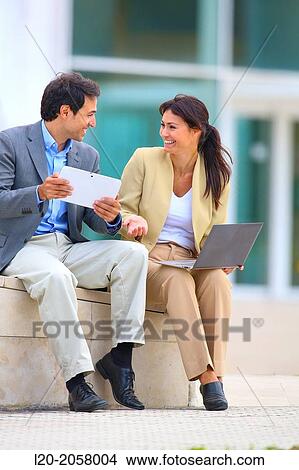 Businesswoman and businessman sitting on business center. San Sebastian Technology Park. Donostia. Gipuzkoa. Basque Country. Spain View Large Photo Image Picture - Businesswoman and businessman sitting on business center. San Sebastian Technology Park. Donostia. Gipuzkoa. Basque Country. Spain. Fotosearch