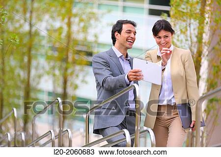 Stock Image - Businesswoman and businessman talking on stairs. business center. San Sebastian Technology Park. Donostia. Gipuzkoa. Basque Country. Spain.. Fotosearch