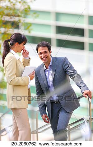 Stock Image - Businesswoman and businessman talking on stairs. business center. San Sebastian Technology Park. Donostia. Gipuzkoa. Basque Country. Spain.. Fotosearch
