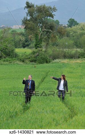 Stock Image - businesswoman and businessman walking at field. Fotosearch