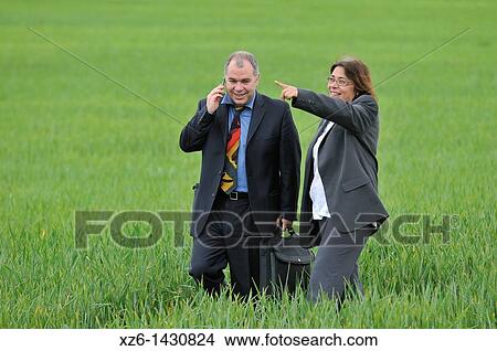 businesswoman and businessman with mobile phone in the field View Large Photo Image Picture - businesswoman and businessman with mobile phone in the field. Fotosearch