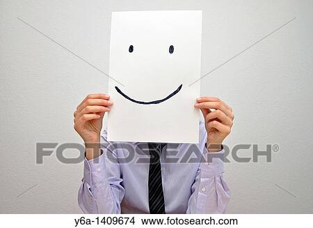Businesswoman holding card with smiley face in front of face View Large Photo Image Picture - Businesswoman holding card with smiley face in front of face. Fotosearch