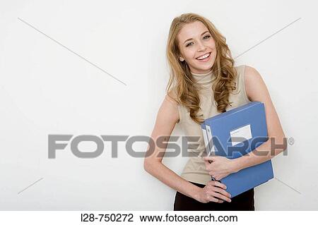 Stock Image - Businesswoman holding file folders, smiling, portrait. Fotosearch