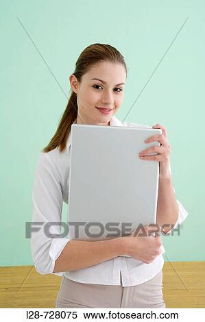 Businesswoman holding laptop, smiling, portrait View Large Photo Image Stock Photography - Businesswoman holding laptop, smiling, portrait. Fotosearch
