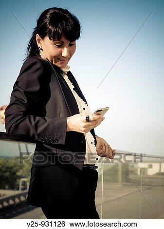 Businesswoman looking at cell phone View Large Photo Image Stock Photograph - Businesswoman looking at cell phone. Fotosearch