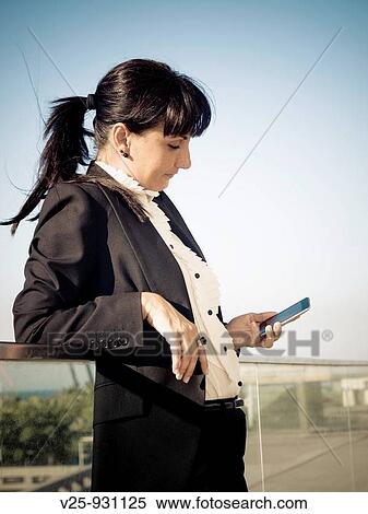 Businesswoman looking at cell phone View Large Photo Image Stock Photography - Businesswoman looking at cell phone. Fotosearch