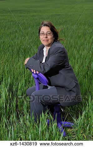 Stock Photo - businesswoman sitting in a chair at field. Fotosearch
