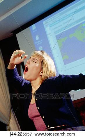 Businesswoman sitting on a desk yawning in an office View Large Photo Image Stock Photo - Businesswoman sitting on a desk yawning in an office. Fotosearch