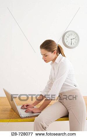 Businesswoman Sitting on Table and Using Laptop View Large Photo Image Stock Photo - Businesswoman Sitting on Table and Using Laptop. Fotosearch