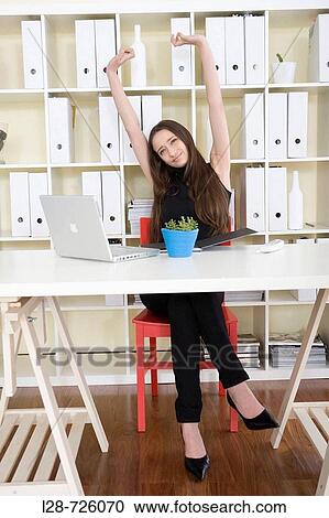 Stock Image - Businesswoman stretching at desk. Fotosearch
