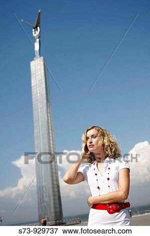 Stock Photo - Businesswoman using cell phone front the Glory Monument in Samara, Samara Region, Russian Federation, Russia. Fotosearch