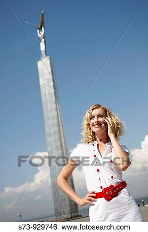 Stock Photograph - Businesswoman using cell phone front the Glory Monument in Samara, Samara Region, Russian Federation, Russia. Fotosearch