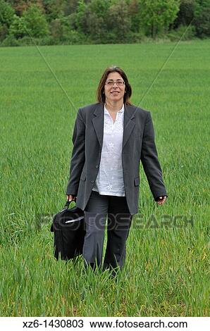 Stock Image - Businesswoman walking in the field. Fotosearch