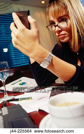 Businesswoman working on a desk with handheld in an office View Large Photo Image Picture - Businesswoman working on a desk with handheld in an office. Fotosearch