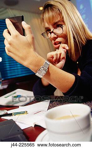 Businesswoman working on a desk with handheld in an office View Large Photo Image Stock Photography - Businesswoman working on a desk with handheld in an office. Fotosearch