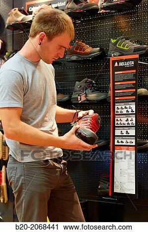 Stock Image - Buying protective boots. Hardware store.. Fotosearch