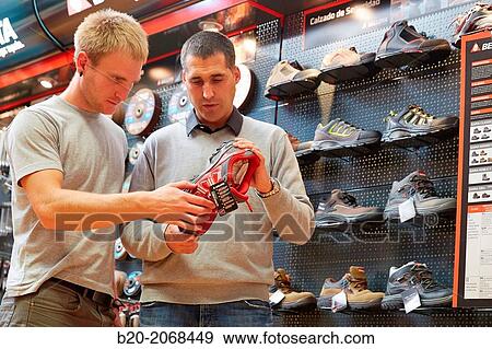 Stock Photo - Buying protective boots. Hardware store.. Fotosearch