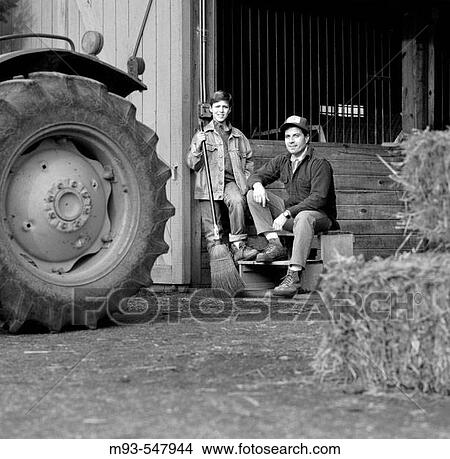 BW Portrait of 30s farmer and teenage son by tractor in front of barn; facing camera View Large Photo Image Picture - BW Portrait of 30s farmer and teenage son by tractor in front of barn; facing camera. Fotosearch