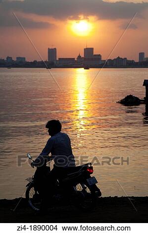 Cambodian motorbike driver waiting for the ferry to cross Tonle sap river in Phnom Penh Cambodia View Large Photo Image Picture - Cambodian motorbike driver waiting for the ferry to cross Tonle sap river in Phnom Penh Cambodia. Fotosearch
