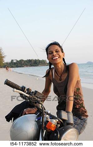 Stock Image - Cambodschanische young woman with a motorcycle on the beach in Sihanoukville. Fotosearch