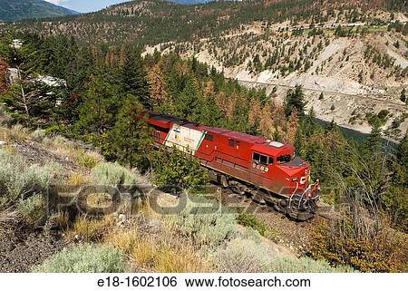 Stock Photograph - Canada, BC, Lytton. Powerful diesel electric engine pulls a freight train through the Thompson River Canyon.. Fotosearch