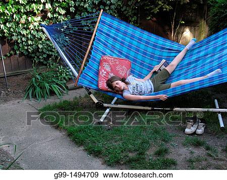 Canada, Ontario, Windsor. Nine year old girl on hammock reading when a dog approaches. View Large Photo Image Stock Photo - Canada, Ontario, Windsor. Nine year old girl on hammock reading when a dog approaches.. Fotosearch