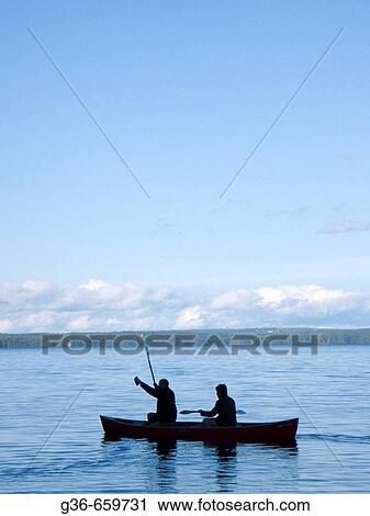 Stock Image - Canoers at sunset in Sebago Lake, Maine. Fotosearch