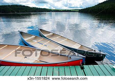 Canoes at dock with blue sky reflecting in water in Bryant Pond, Maine View Large Photo Image Picture - Canoes at dock with blue sky reflecting in water in Bryant Pond, Maine. Fotosearch