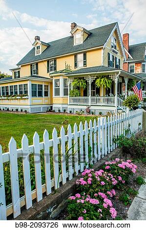 Cape May is America's first seaside resort. It has the largest collection of Victorian Architecture in the United States. A white picket fence, american flag and a flower bed is distinctly a nostalgic image of early 20th Century small town America View Large Photo Image Stock Photograph - Cape May is America's first seaside resort. It has the largest collection of Victorian Architecture in the United States. A white picket fence, american flag and a flower bed is distinctly a nostalgic image of early 20th Century small town America. Fotosearch