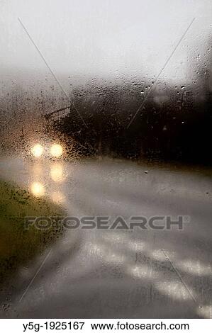 Stock Photo - car driving in heavy rain on rural country road. Fotosearch