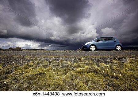 Stock Photo - Car passing in the road between Eldhraun mossy lava fields Iceland. Fotosearch