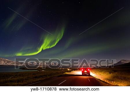 Stock Photo - Car stopped on road with Northern Lights, Eyjafjordur Iceland. Fotosearch