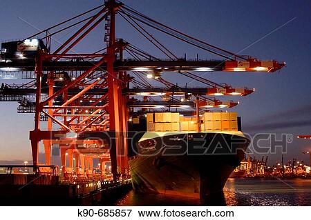 Stock Photo - Cargoship at the container terminal? Eurokai? in Hamburg harbor off-loading container in the early evening with the help of huge cranes, Germany, Europe. Fotosearch