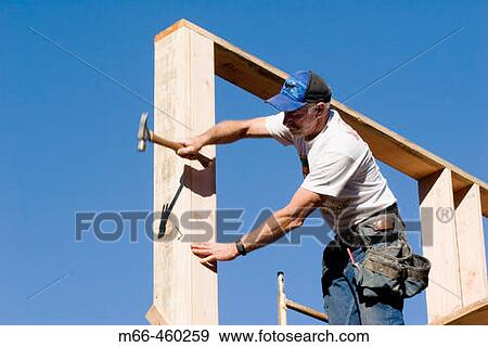 Carpenter reaching to hammer a nail into the corner stud of a two-story room while standing on scaffolding. View Large Photo Image Stock Photo - Carpenter reaching to hammer a nail into the corner stud of a two-story room while standing on scaffolding.. Fotosearch