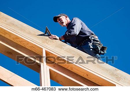 Carpenter walking along a roof rafter with a speed square at a construction site. View Large Photo Image Stock Image - Carpenter walking along a roof rafter with a speed square at a construction site.. Fotosearch