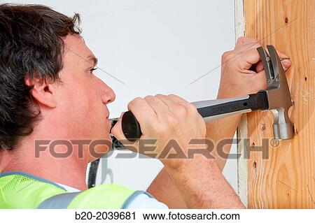 Stock Image - Carpenter with hammer with carbon fiber handle. Construction of residential building. Donostia. San Sebastian. Gipuzkoa. Basque Country. Spain.. Fotosearch