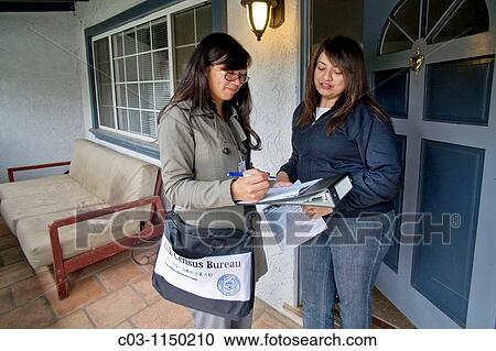 Stock Image - Carrying her official shoulder bag, an Asian-American 2010 U. S. Census enumerator interviews a Hispanic homeowner in Southern California. Administered every ten years, the census is an important tool of efficient government.. Fotosearch