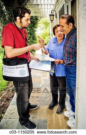 Stock Photography - Carrying his official shoulder bag, a 2010 U. S. Census enumerator shows his ID card while interviewing a Hispanic married couple in Southern California. Administered every ten years, the census is an important tool of efficient government.. Fotosearch