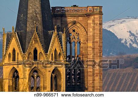 Stock Image - Cathedral of Rouffach, gothic towers in front of vineyards and snowy Vosges, Alsace, France. Fotosearch