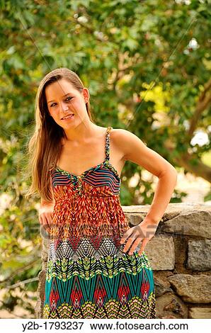 Stock Photo - Caucasian 20 year old brown haired female model wearing multi colored dress on stone wall. Fotosearch