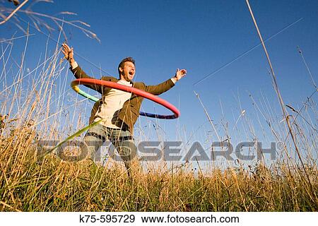 Stock Photo - Caucasian, age 30's to 40? s, hula hoop, exhuberance, field, blue sky, happy, joyful. Fotosearch
