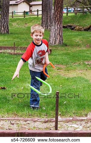 Stock Photo - Caucasian boy, 5-10, playing with plastic horseshoes. Fotosearch