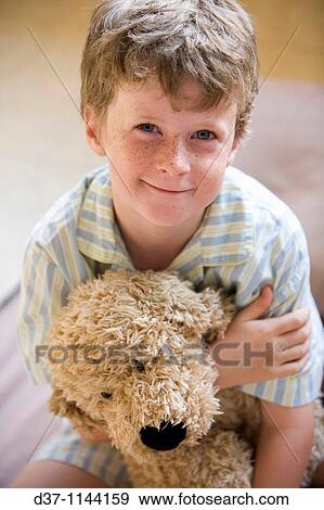 Stock Photo - Caucasian boy holding a cuddly toy in bed. Fotosearch