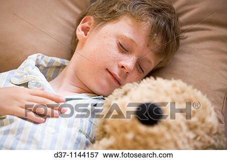 Stock Photo - Caucasian boy sleeping with a cuddly toy in bed. Fotosearch