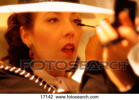 Caucasian brunette woman wearing a white hat applying eye make up holding a hand mirror View Large Photo Image Stock Image - Caucasian brunette woman wearing a white hat applying eye make up holding a hand mirror. Fotosearch