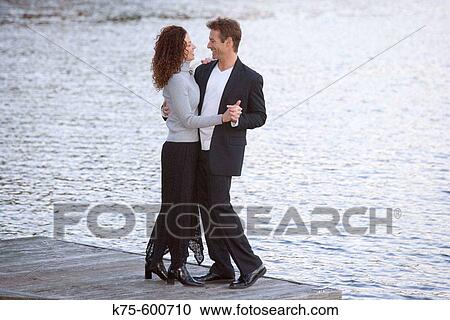 Stock Image - Caucasian couple, ages 30? to 40? s, dock, lake, dancing. Fotosearch