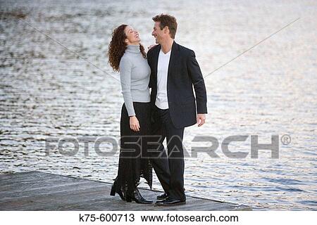 Stock Image - Caucasian couple, ages 30's to 40? s, dock, lake, laughing. Fotosearch
